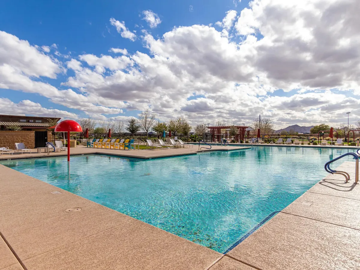 A spacious pool area featuring a water slide, numerous lounge chairs, and a dedicated play zone for children. The setting is playful and relaxed, signaling opportunities for family gatherings and child-friendly fun.