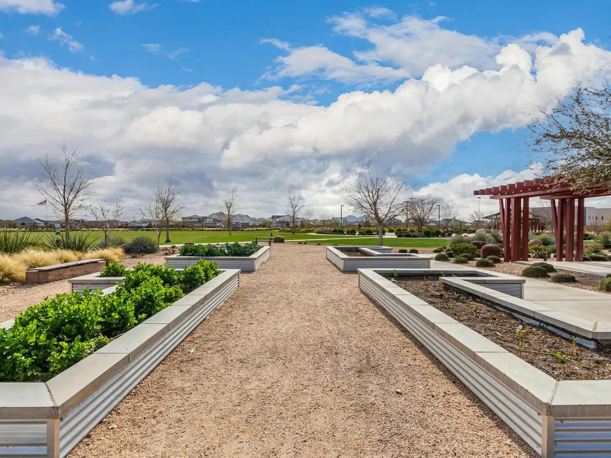 A peaceful landscaped garden with neatly maintained beds, a winding walking path, and a pergola inviting relaxation or social gatherings. The setting is open-air, lush, and designed for outdoor enjoyment year-round.